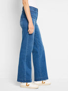 Medium blue high-rise wide-leg jeans with visible pockets and stitching, worn by a person from the side.