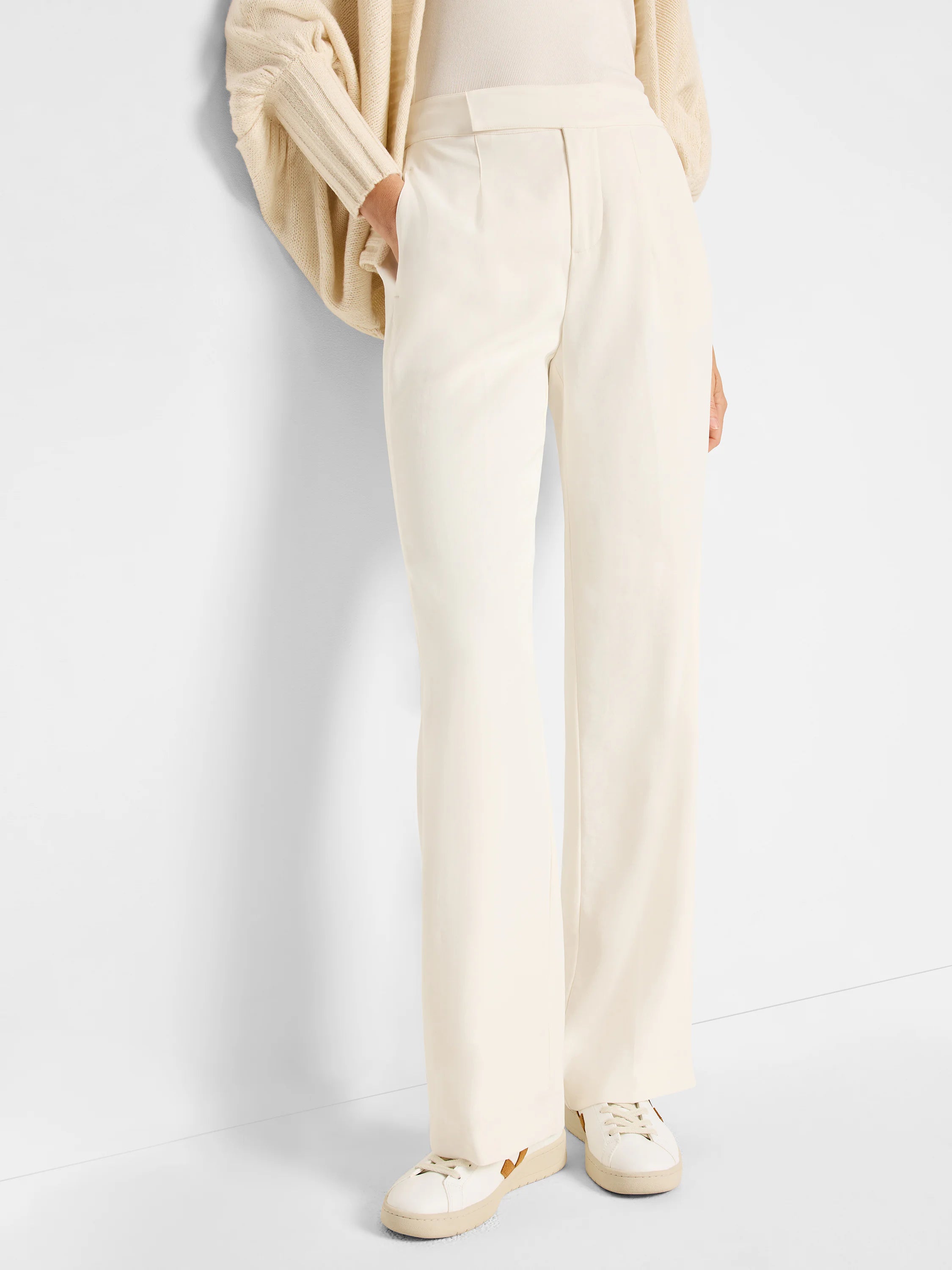 Off-white wide-leg trousers. High-waisted, with a flat front. Model is wearing off-white sneakers.