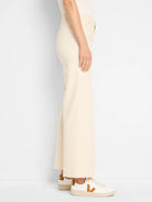 Ecru wide leg jeans with a frayed hem, shown worn from the side.