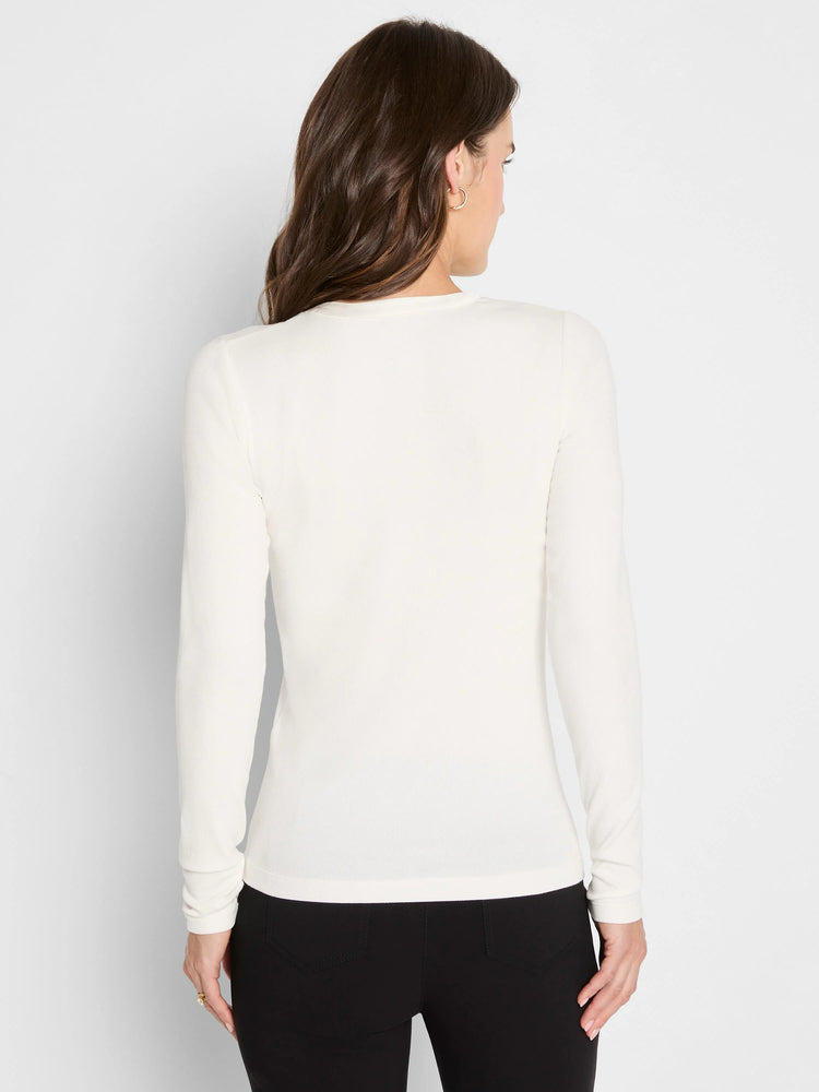 Back view of a woman wearing a cream, long-sleeve, fitted ribbed knit top.