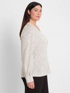 Light grey V-neck knit top with dark flecks & subtle shimmer. Long sleeves have gathered cuffs.