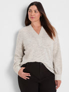 Off-white ribbed knit top with dark speckles and subtle shimmer, V-neck, and long cuffed sleeves.