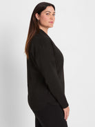 Black long-sleeved top with fine horizontal sparkle stripes. Features a relaxed fit and a draped neckline.