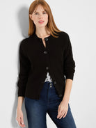 Black waffle knit cardigan with a round neck and dark button-front closure.