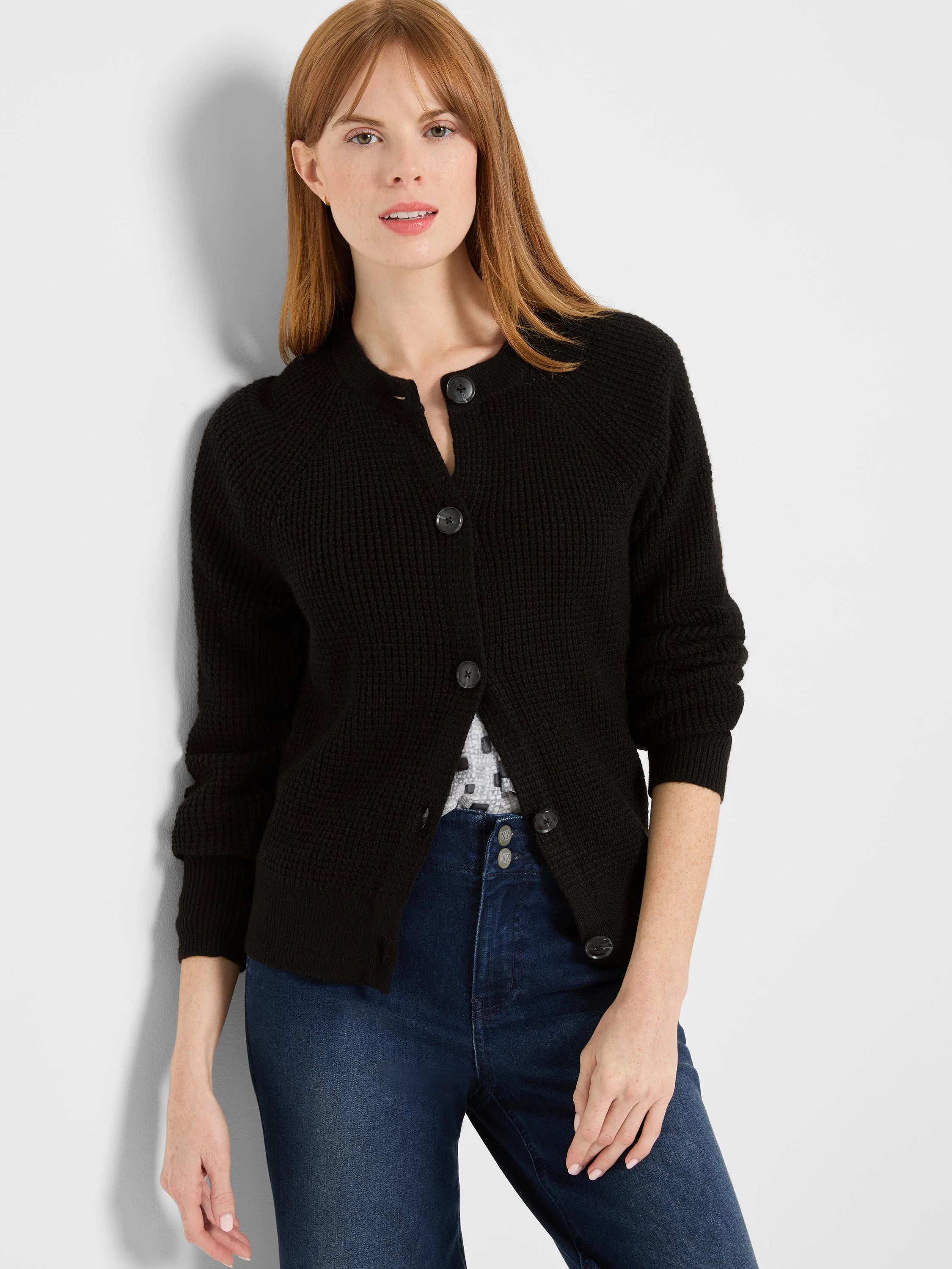Black waffle knit cardigan with a round neck and dark button-front closure.