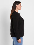 Black waffle knit cardigan with a crew neck and long sleeves, shown from the side on a woman.