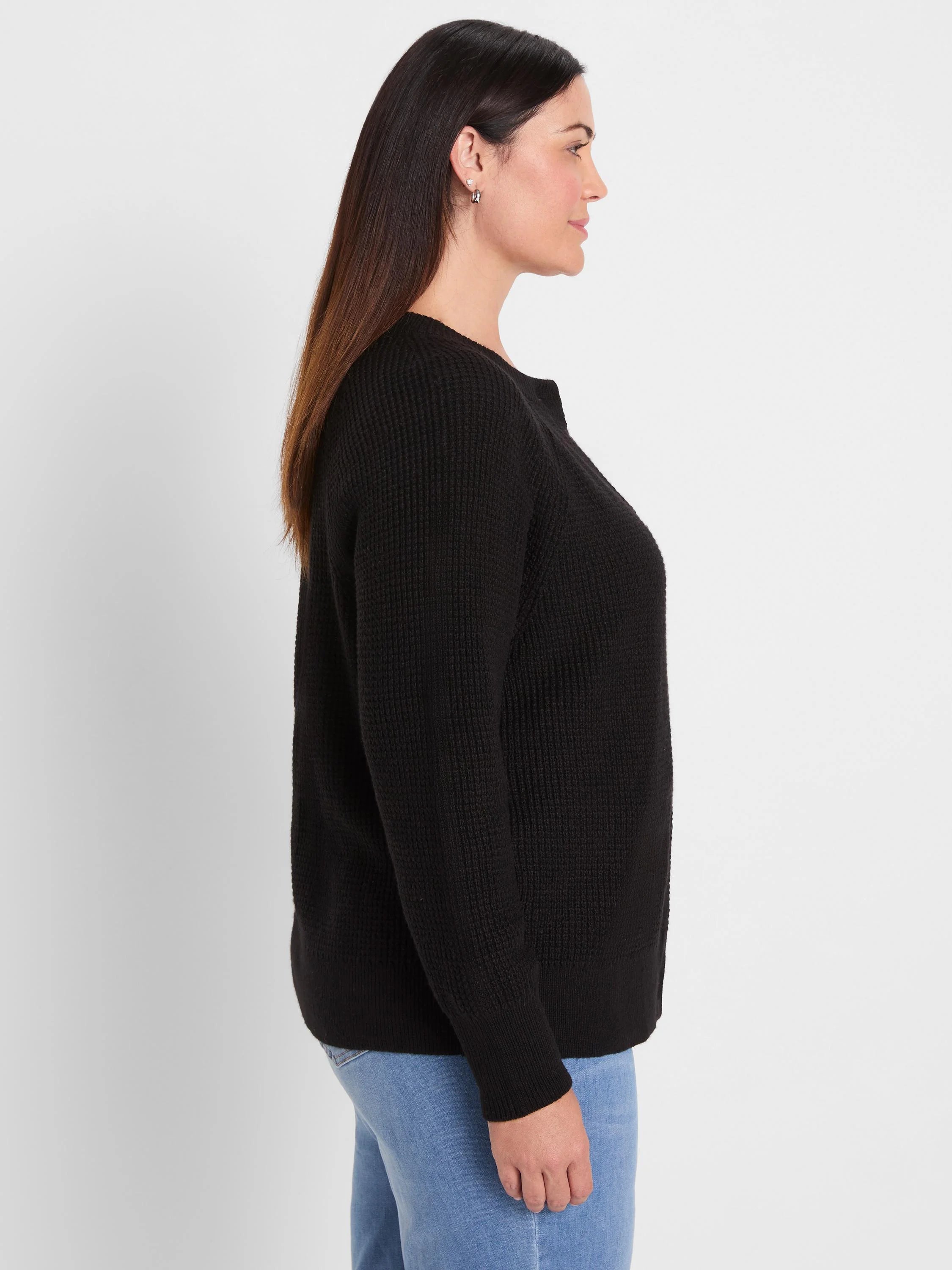 Black waffle knit cardigan with a crew neck and long sleeves, shown from the side on a woman.