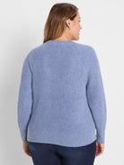 Dusty blue waffle tuck knit cardigan on woman, back view. Features raglan sleeves and ribbed hem/cuffs.