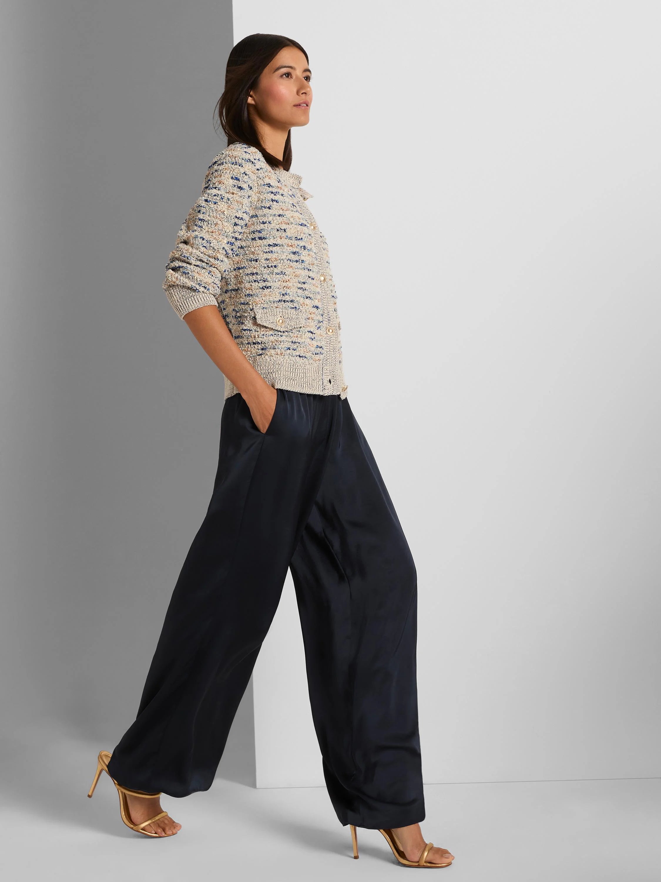 Cream knit jacket with textured blue and tan flecks. Features gold buttons and two small flap pockets.