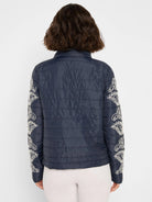 Navy quilted puffer bomber jacket with cream paisley embroidery on sleeves, viewed from behind.