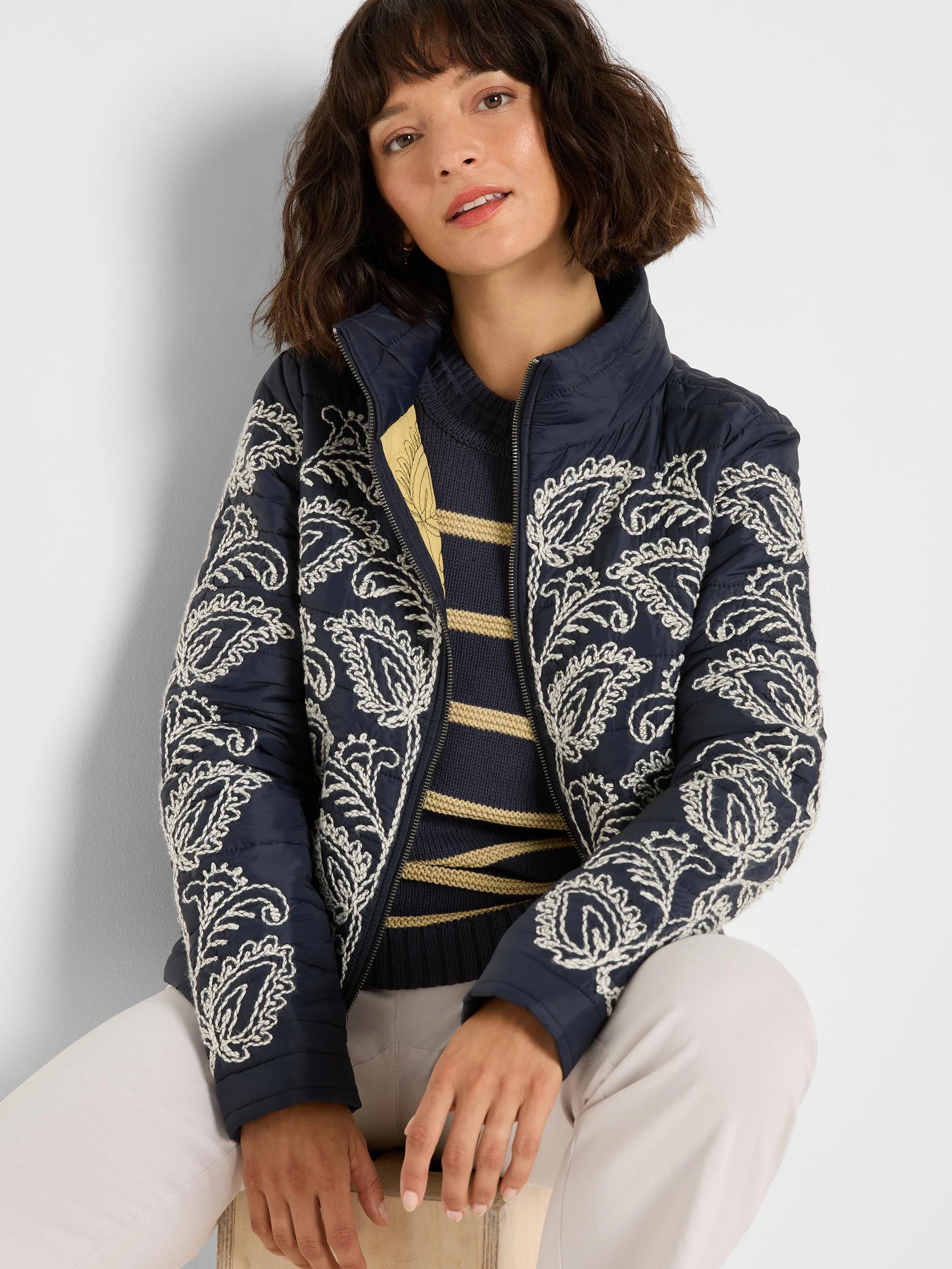 Navy puffer bomber jacket with prominent cream floral embroidery throughout, high collar, and zip front.