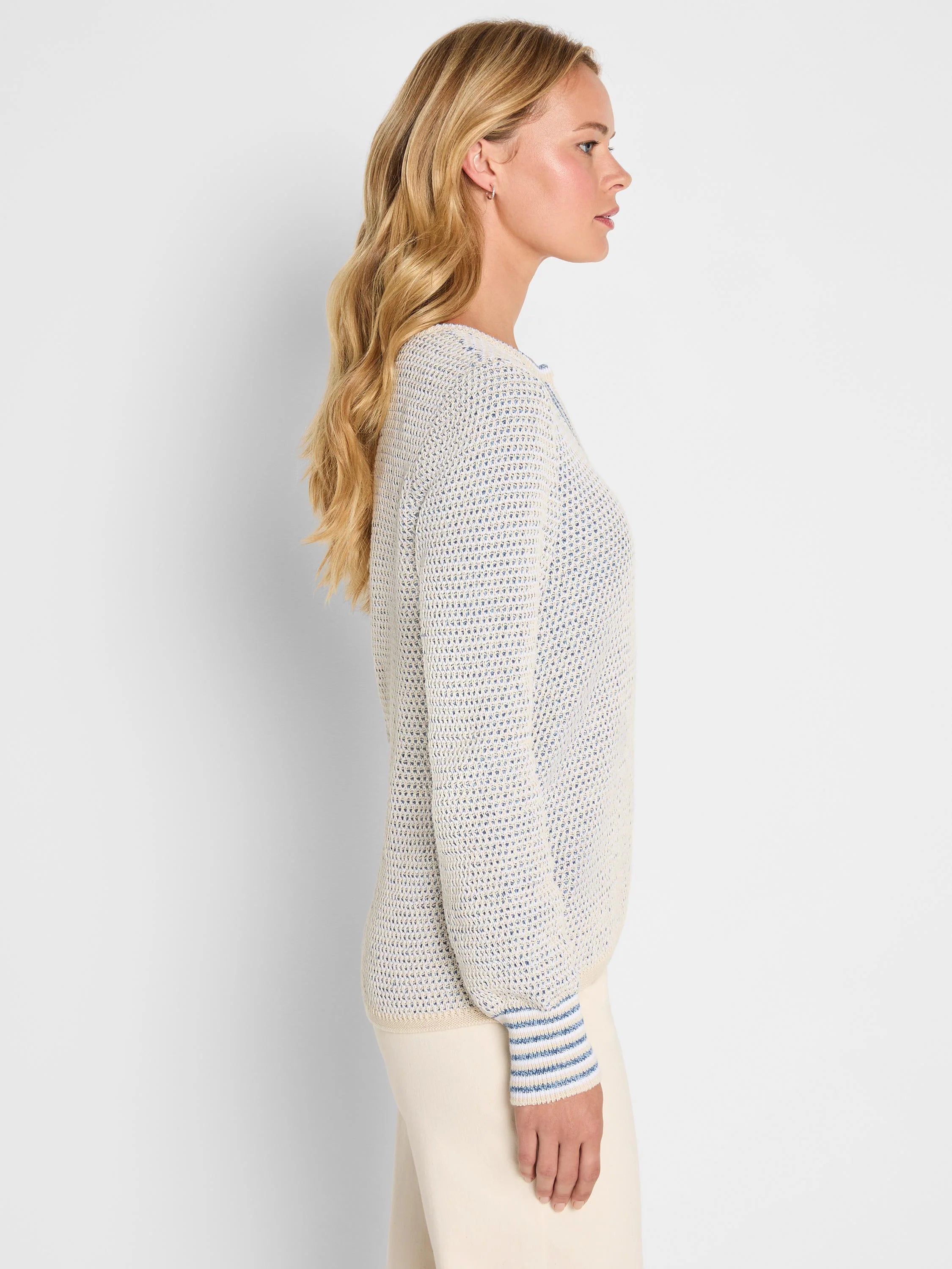 Cream & blue tuck texture sweater on model, side view. Features split neck and striped ribbed cuffs.