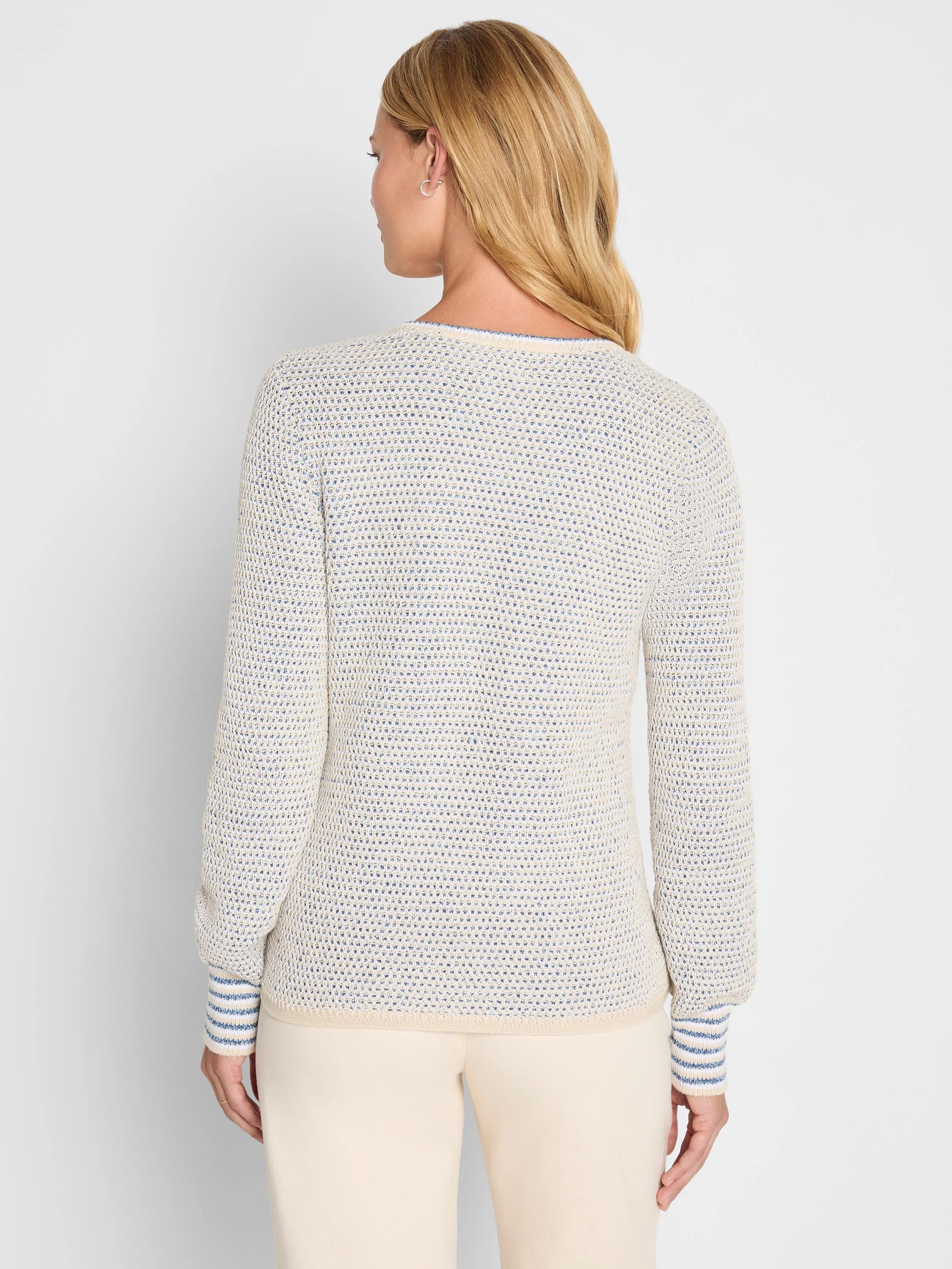 Back of a cream sweater with blue tuck texture. Features blue striped cuffs and a blue trim on the back neckline.