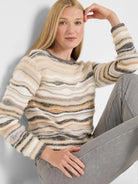 Wavy striped sweater in cream, tan, and shades of grey, featuring fuzzy textured sections between knitted bands.