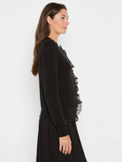 Black knit cardigan with sheer ruffles along button front and hem.