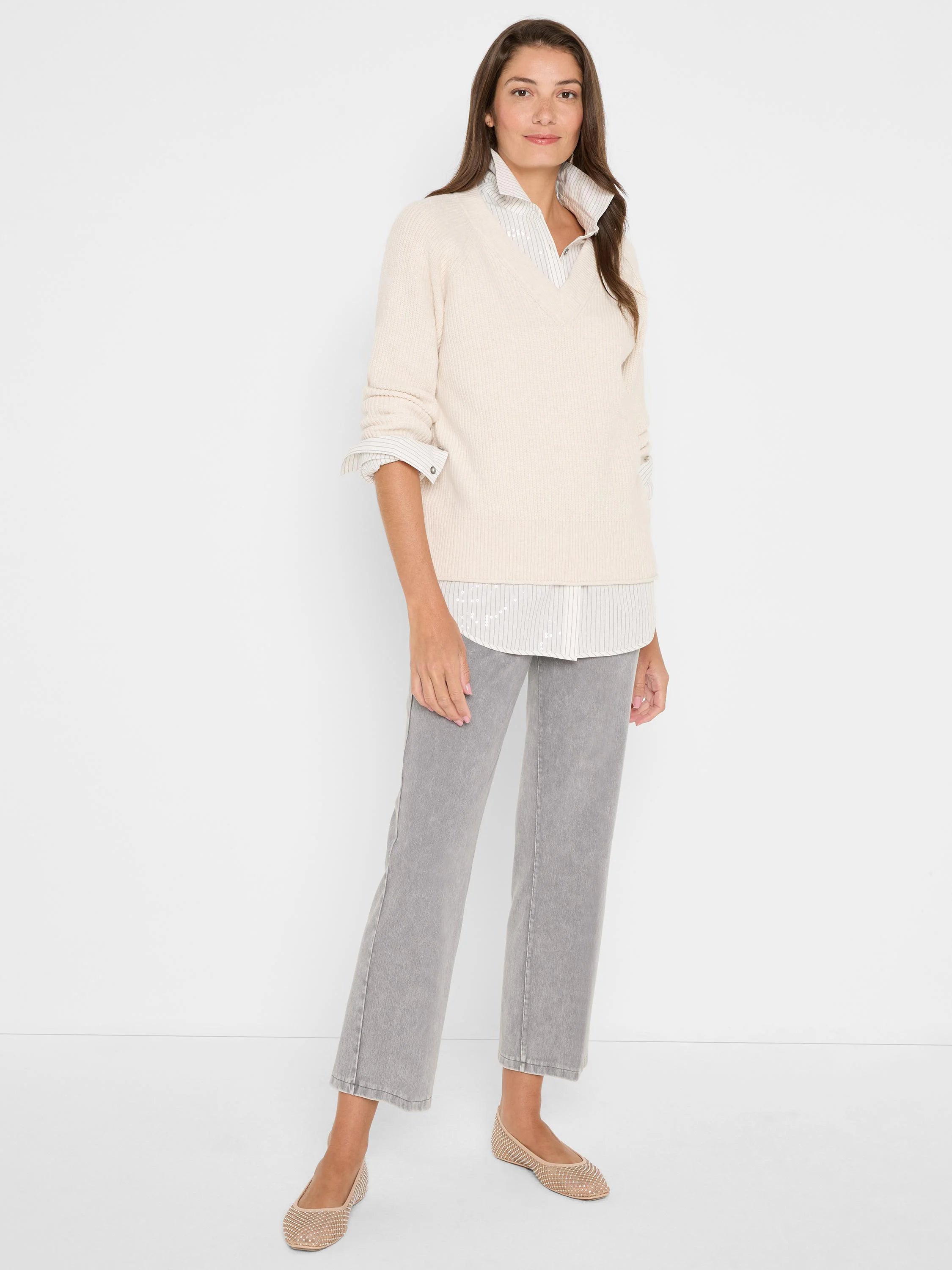Light beige V-neck shaker stitch sweater with long, rolled sleeves.