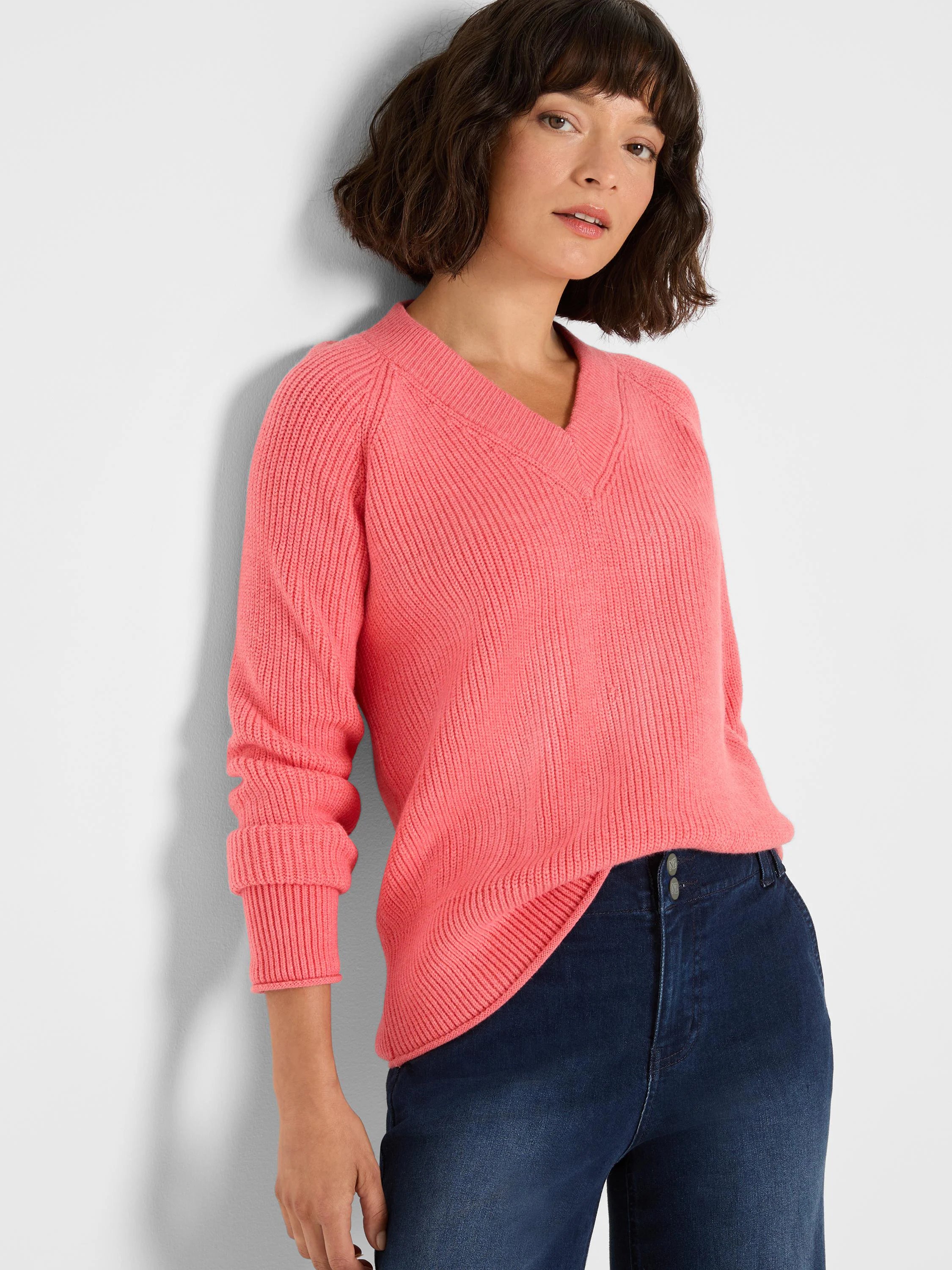 Coral pink V-neck shaker stitch sweater. Features ribbed cuffs, a relaxed fit, and small side slits.