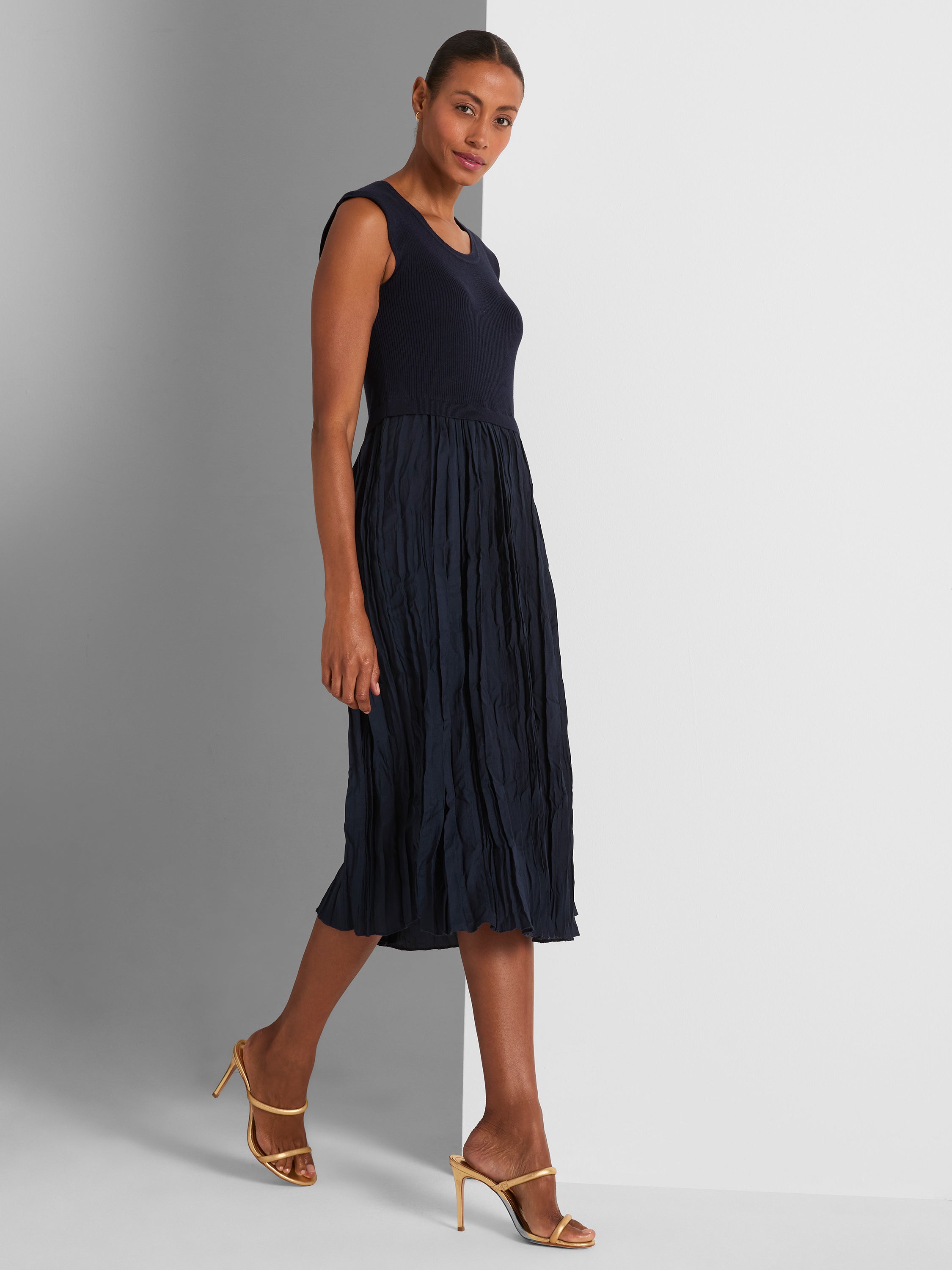 Navy sleeveless midi dress with a fitted ribbed knit bodice and a voluminous, crinkled pleated skirt.