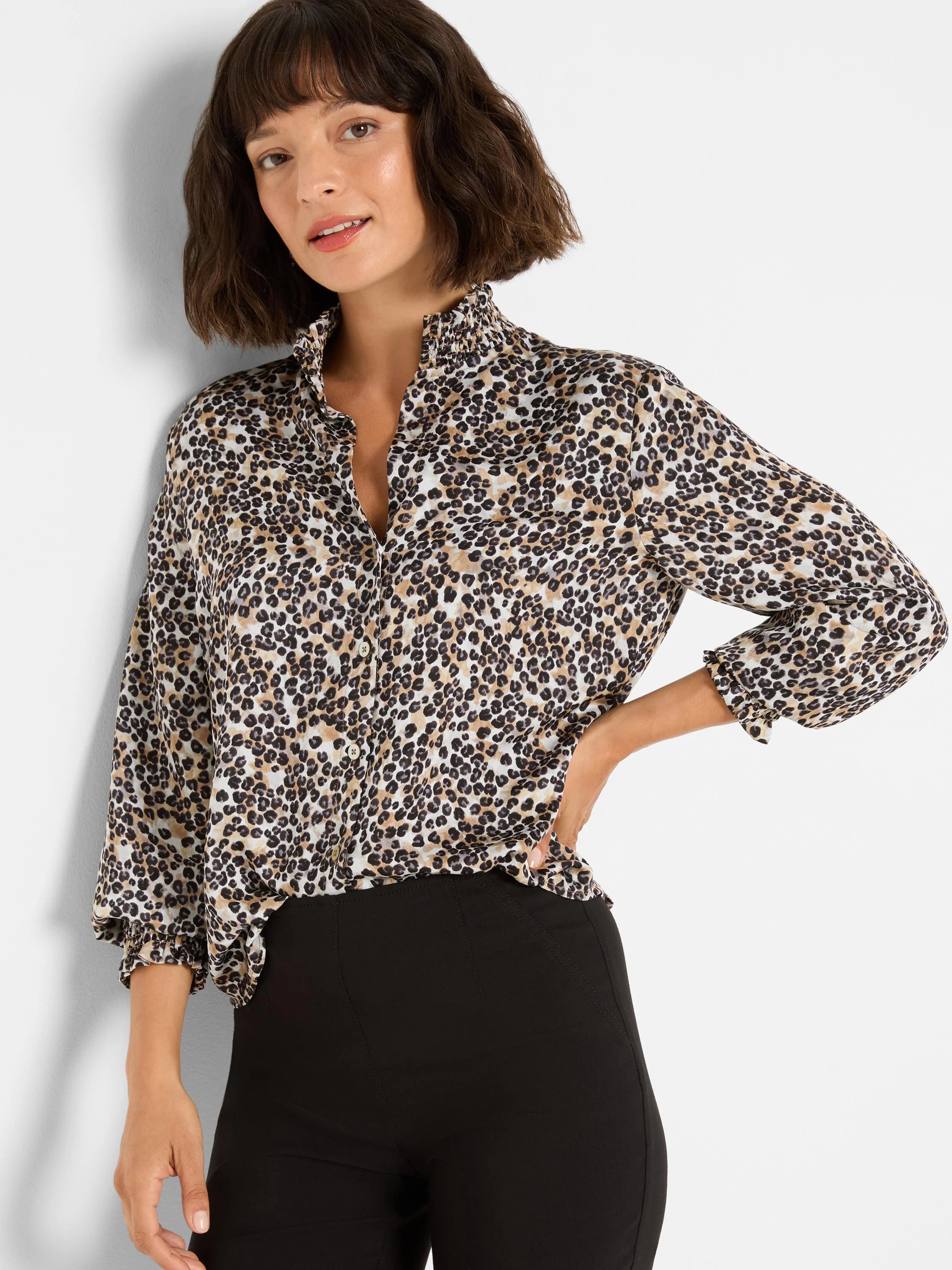 Leopard print top with cream, tan, and dark brown spots. Features a ruffled stand-up collar and 3/4 smocked sleeves.
