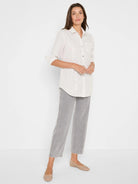 Cream button-up shirt with thin gray vertical stripes & scattered subtle sequins. Long sleeves are rolled.
