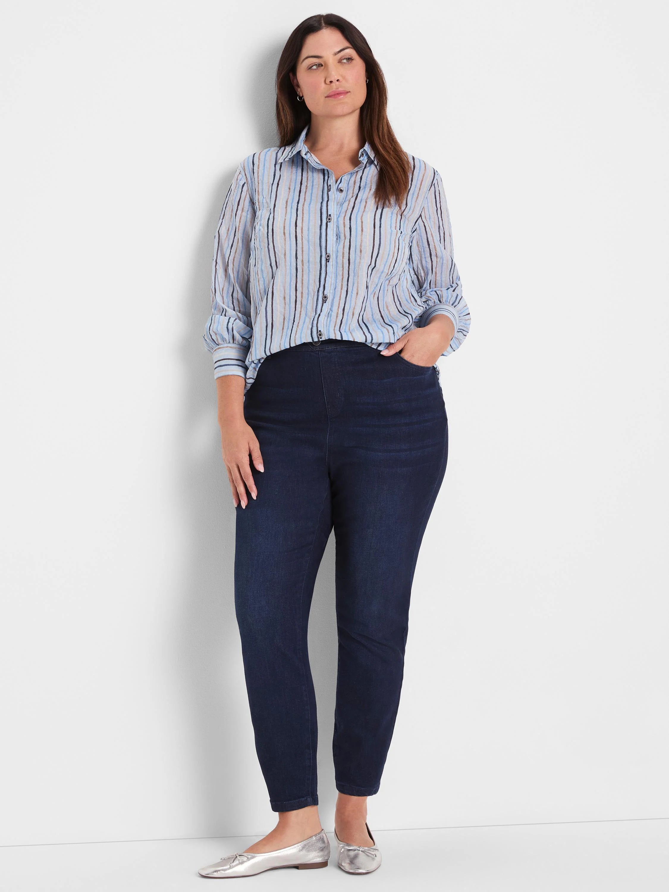 Light blue collared shirt with painted vertical stripes in shades of blue and brown; sleeves rolled.