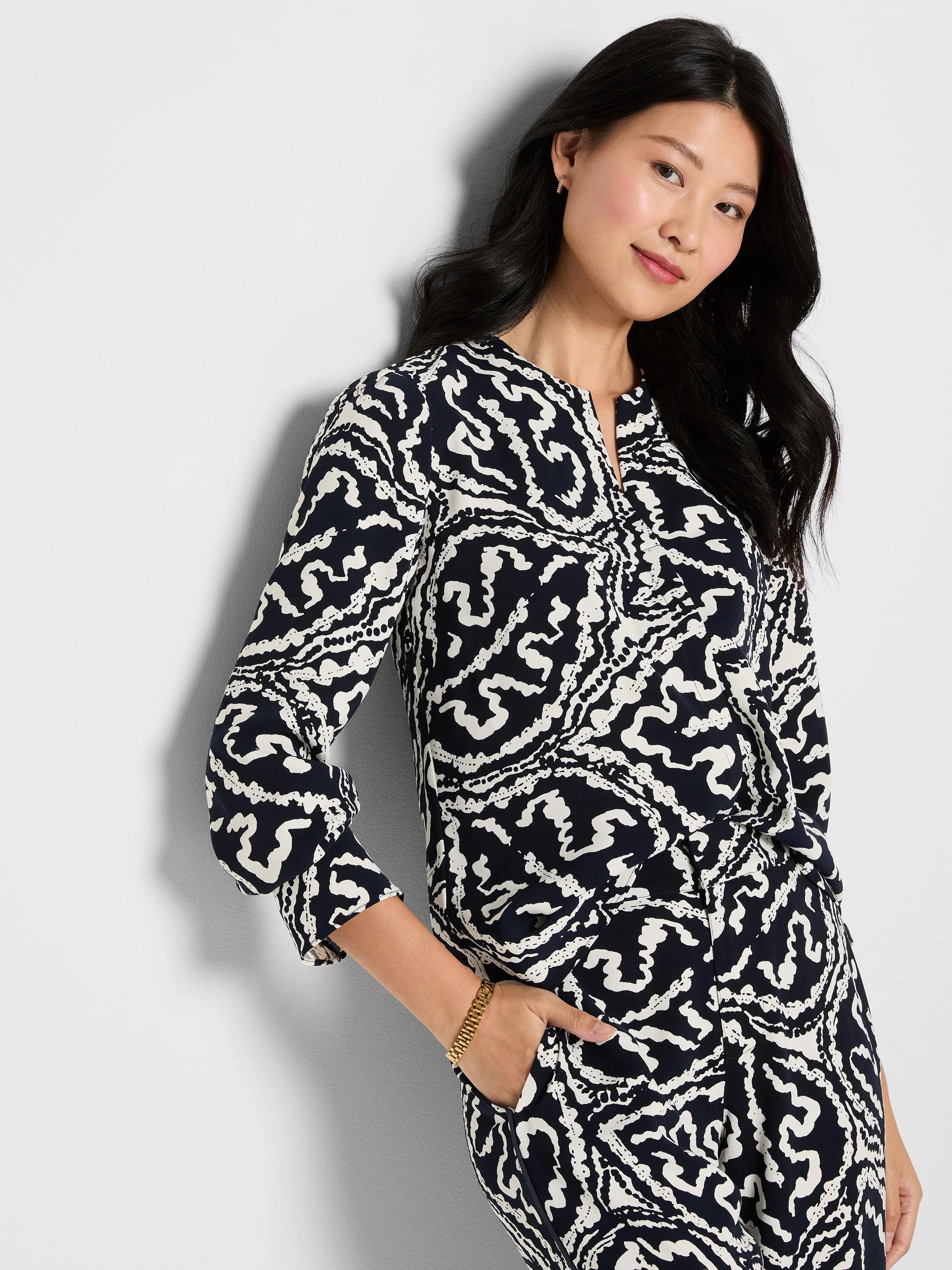 Off-white abstract pattern on dark indigo long-sleeved crepe top. Features a notch V-neck.