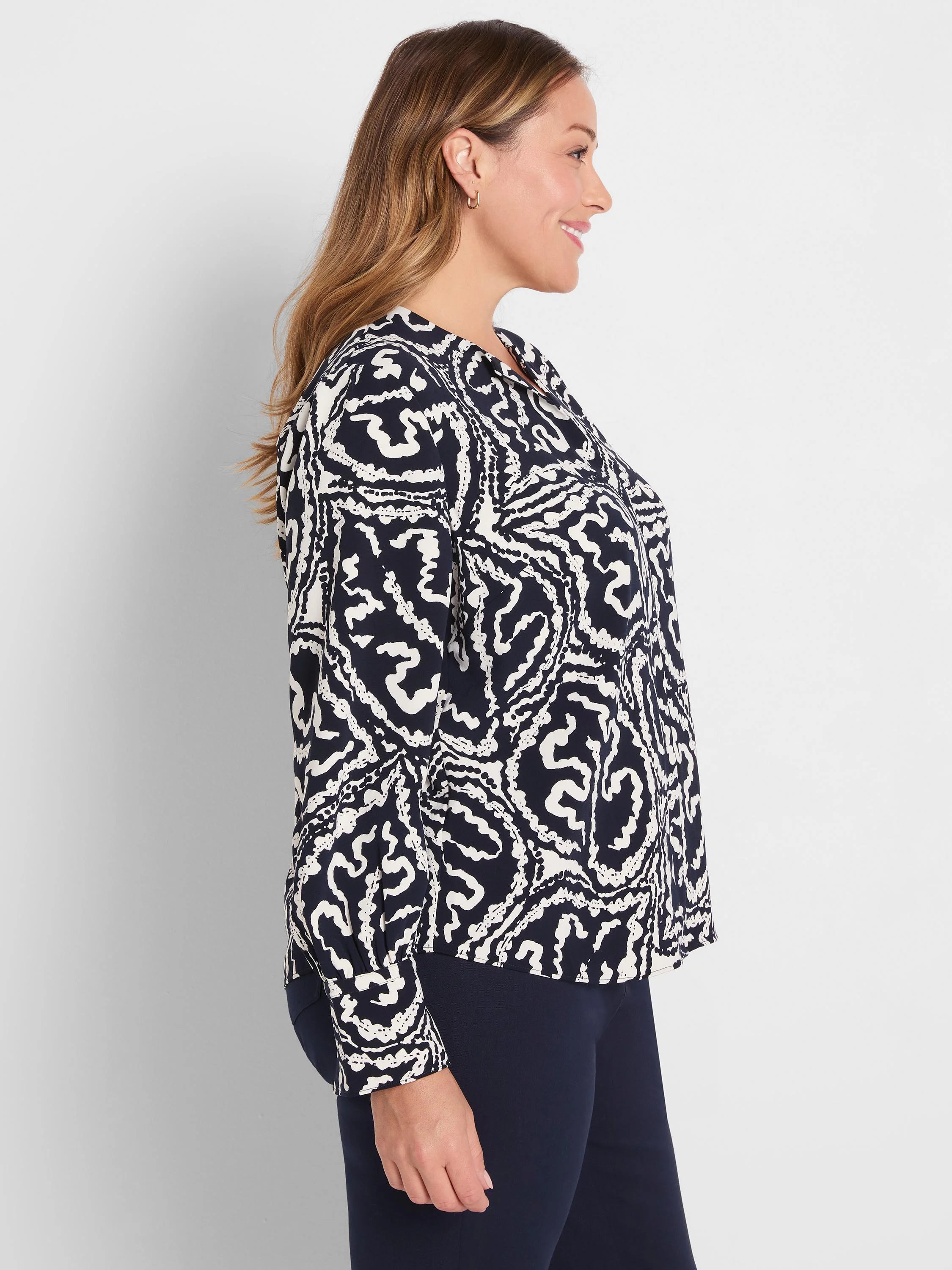 Indigo top with white abstract wavy pattern, long-sleeved and collared. Worn by a woman in profile.