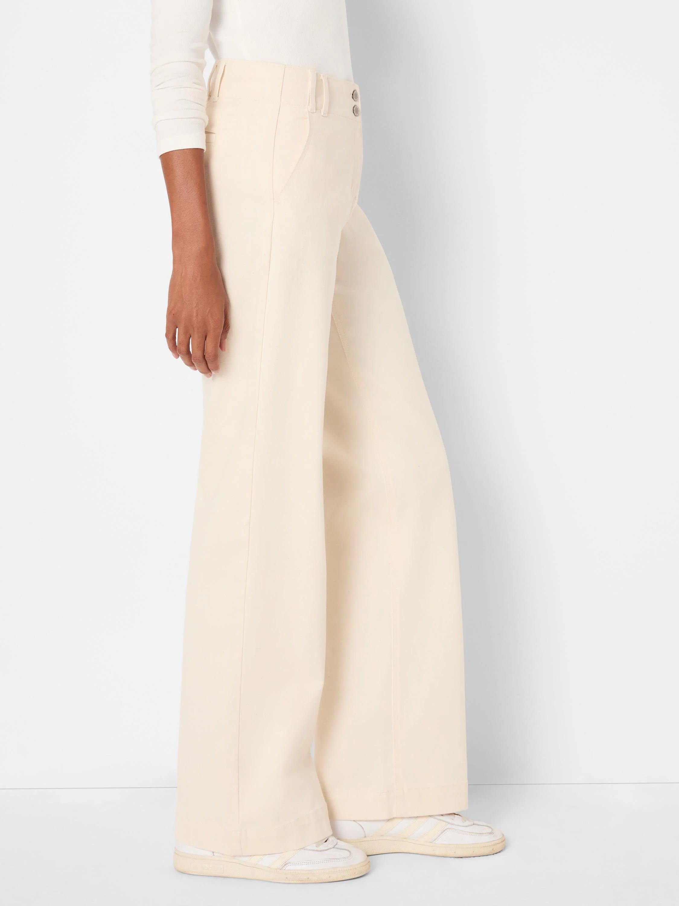 Off-white wide leg trouser jeans with a high waist, two silver buttons, and front pockets.