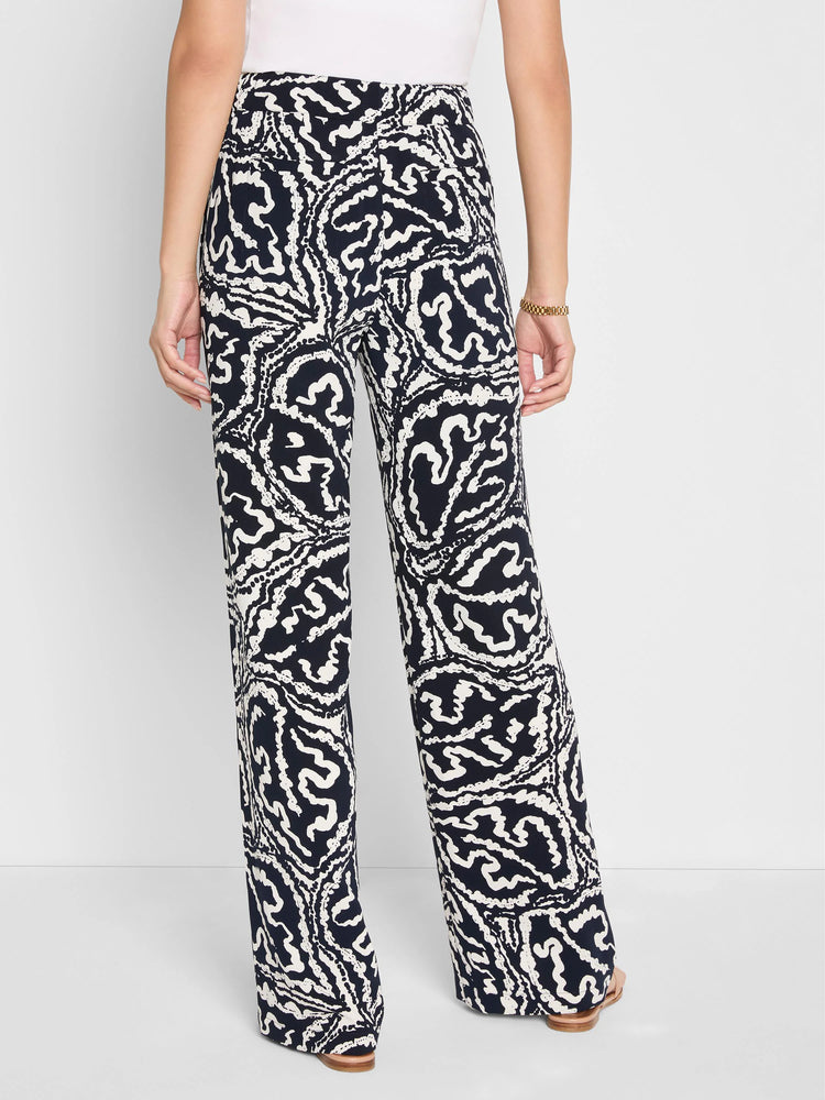 Indigo wide-leg pants with a high-contrast swirling white leaf pattern. Shown worn from behind.