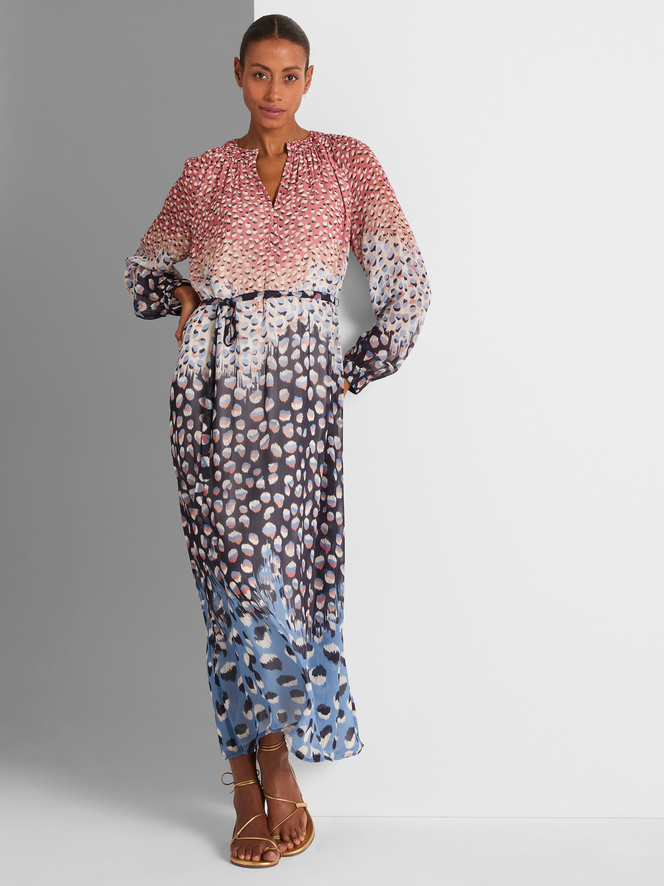 Flowing sheer maxi dress in a pink and navy abstract spotted print, featuring long gathered sleeves and a thin waist belt.