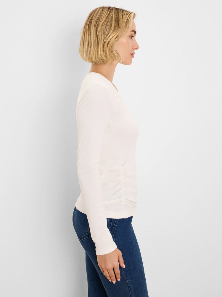 Off-white rib knit long-sleeve tee with side ruching, shown on a model in profile.