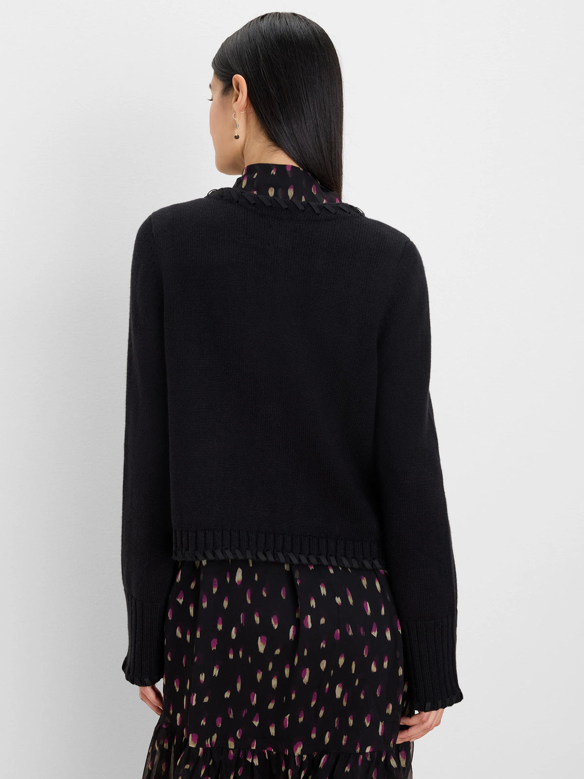 Black knit cardigan jacket, cropped, with black ribbon lacing detail at the back collar, cuffs, and bottom hem.