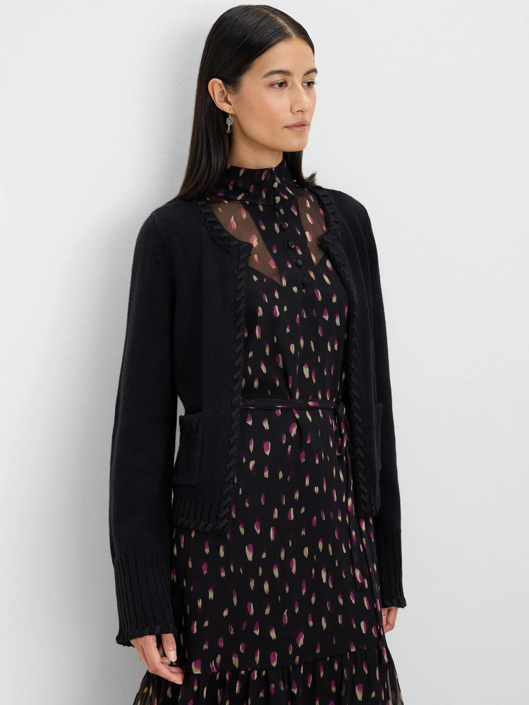 Black short cardigan with braided trim along edges and pockets, plus rib-knit cuffs.