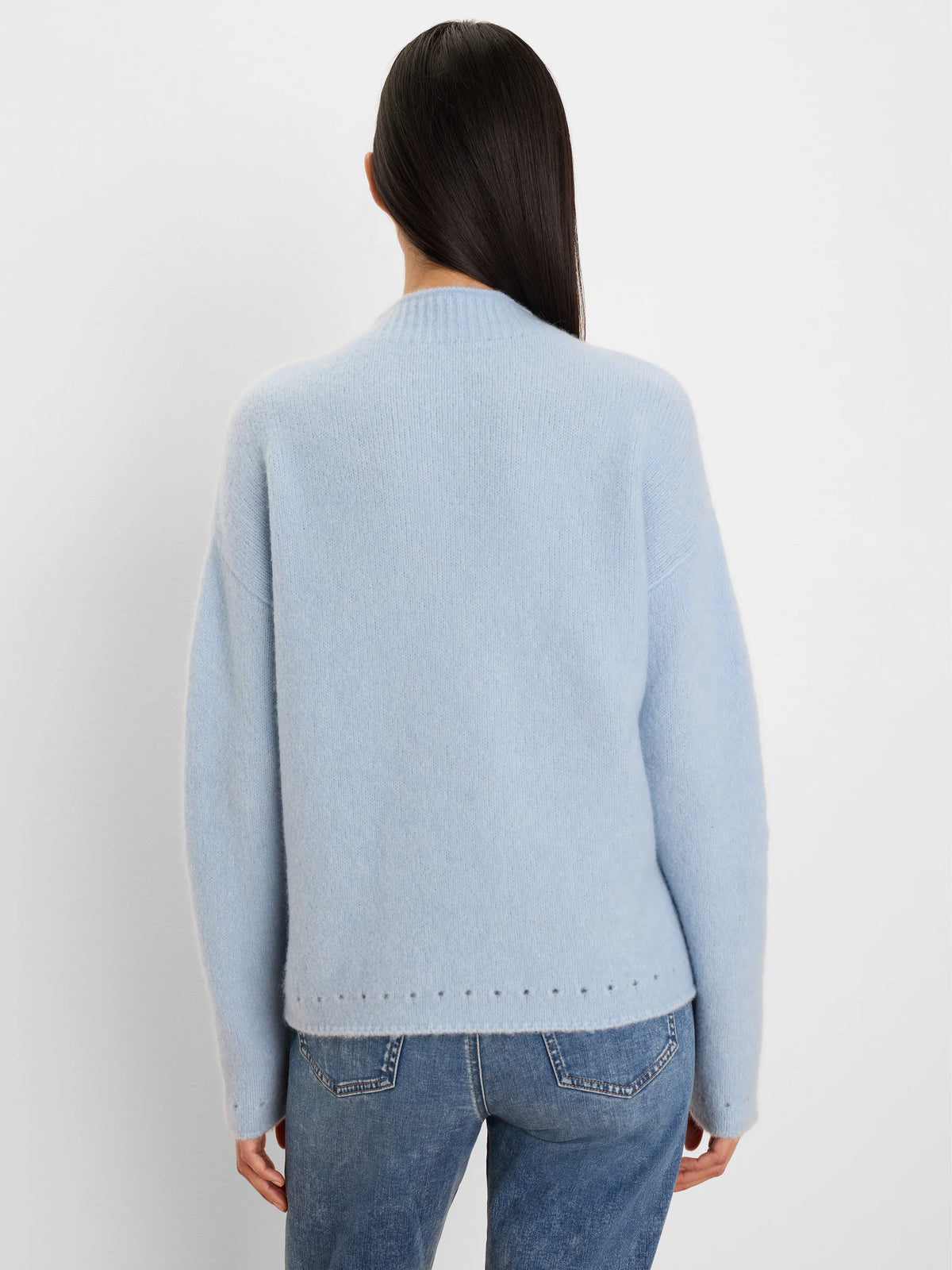 Pale blue fuzzy knit sweater with a mock neck and small dark perforations along the bottom hem and sleeves.