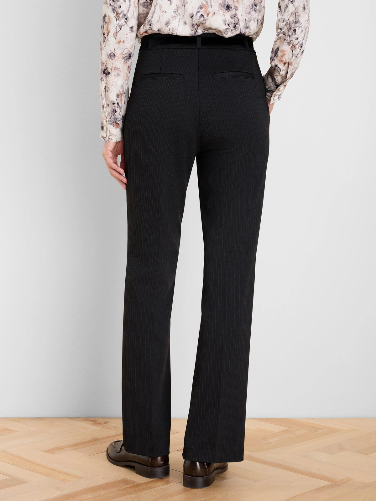 Black pinstripe bootcut pants, seen from the back. Features subtle thin stripes and two horizontal back pockets.