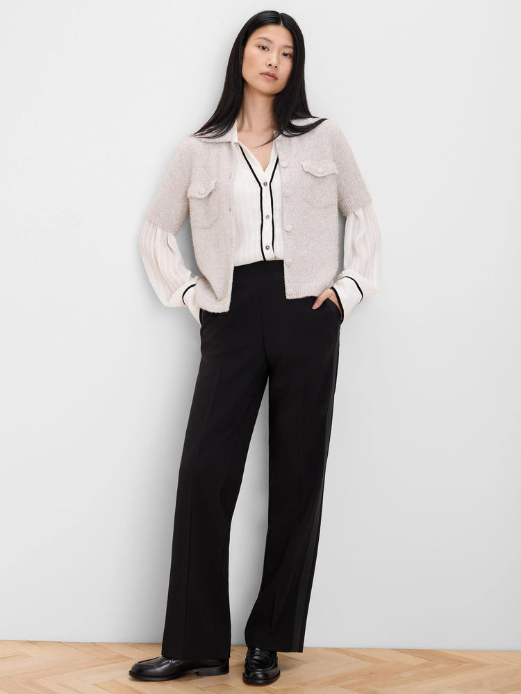 White shirt with black velvet trim on the V-neckline, button placket, and pleated cuffs.