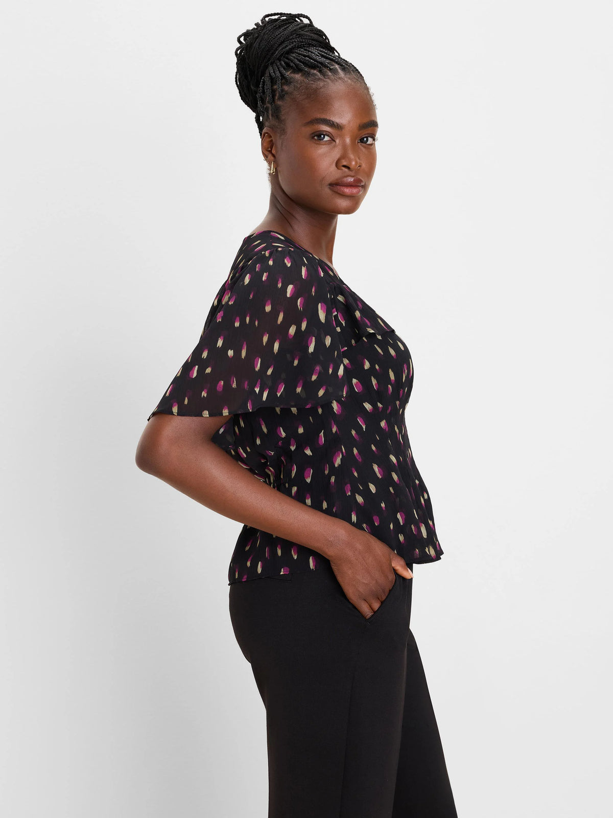 Black sheer top with pink and gold abstract strokes. Features flutter sleeves and a V-neck.