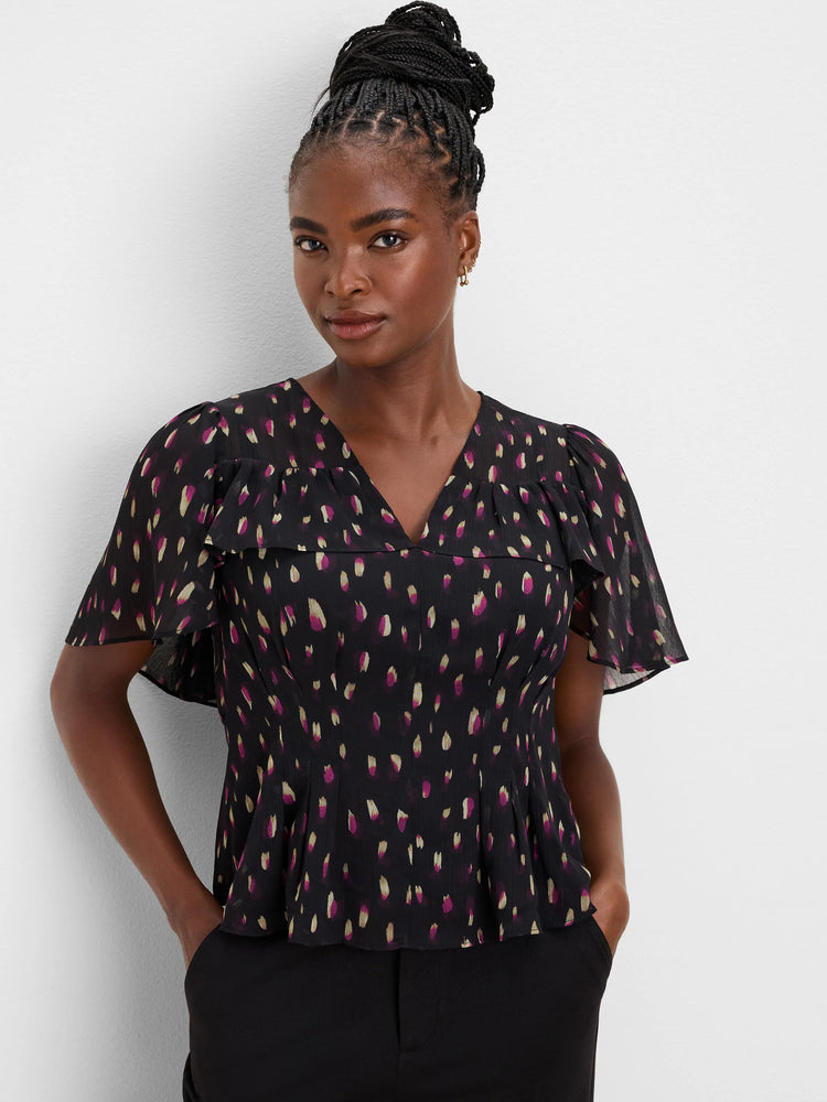 Black top with magenta and gold brushstroke spots, V-neck, short flutter sleeves, and a relaxed fit.