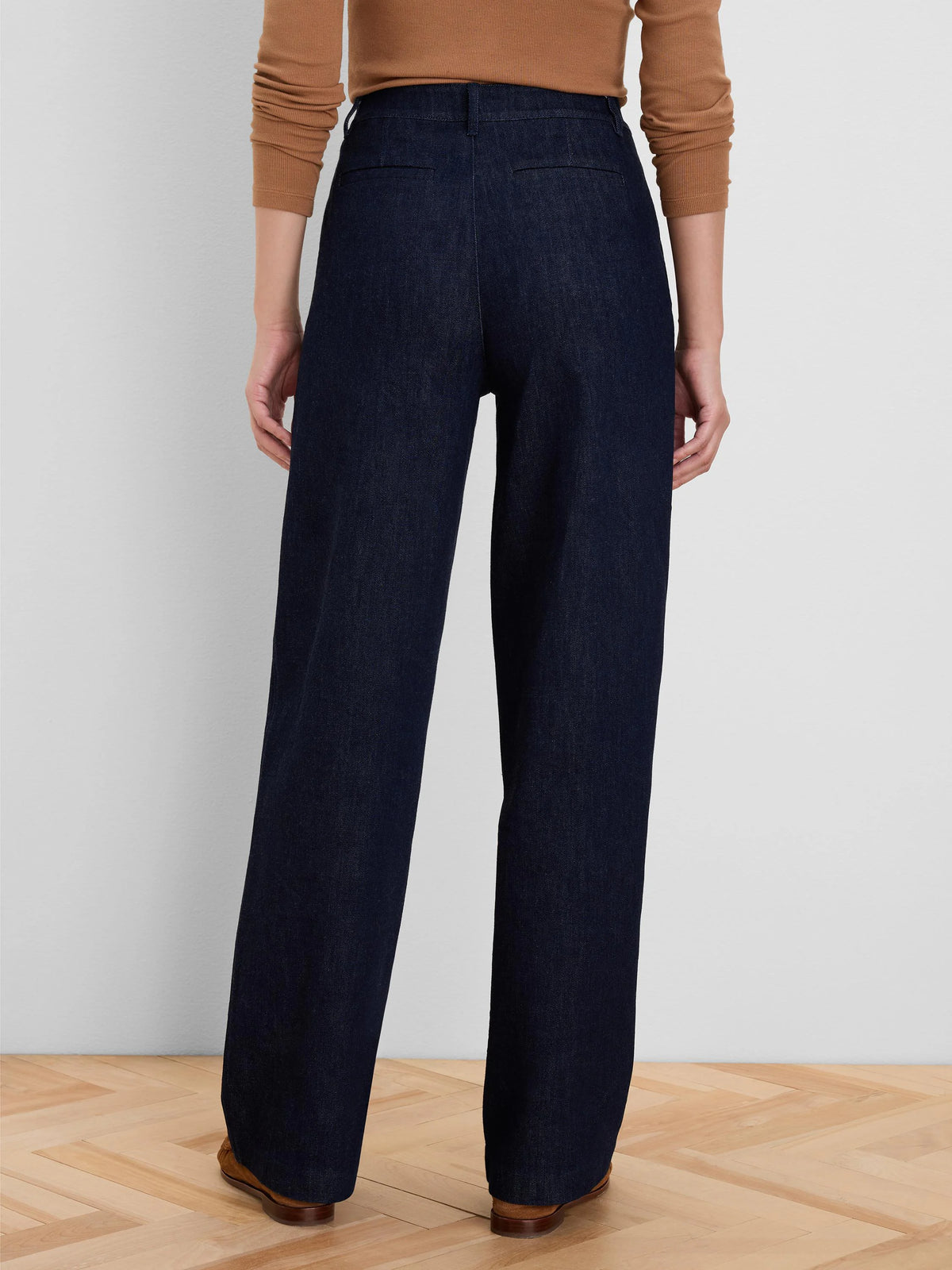 Dark indigo wide-leg jeans from the back. High-waisted, clean design with subtle horizontal welt pockets.