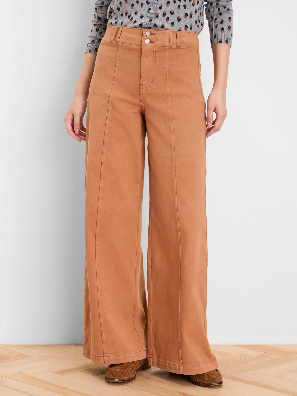 Rust wide leg jeans with a double button high waist and prominent vertical front seams.
