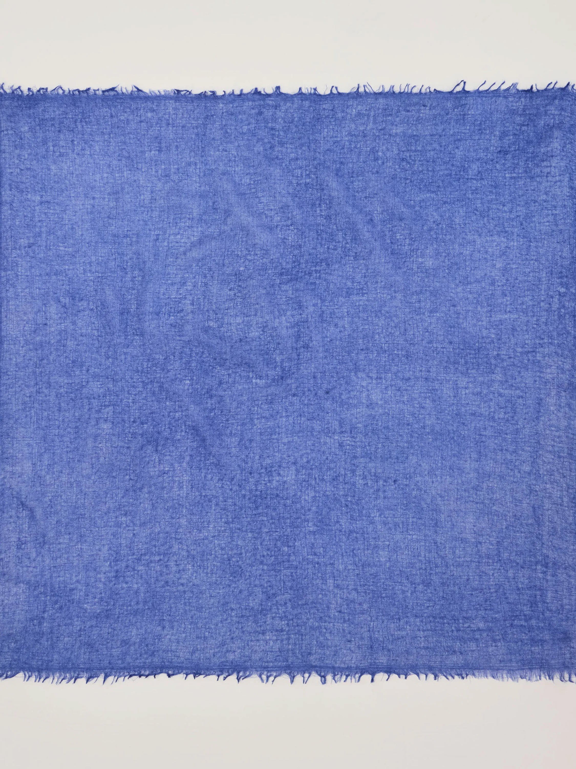 Cobalt blue cashmere neck scarf with a visible, loose weave texture and frayed edges.