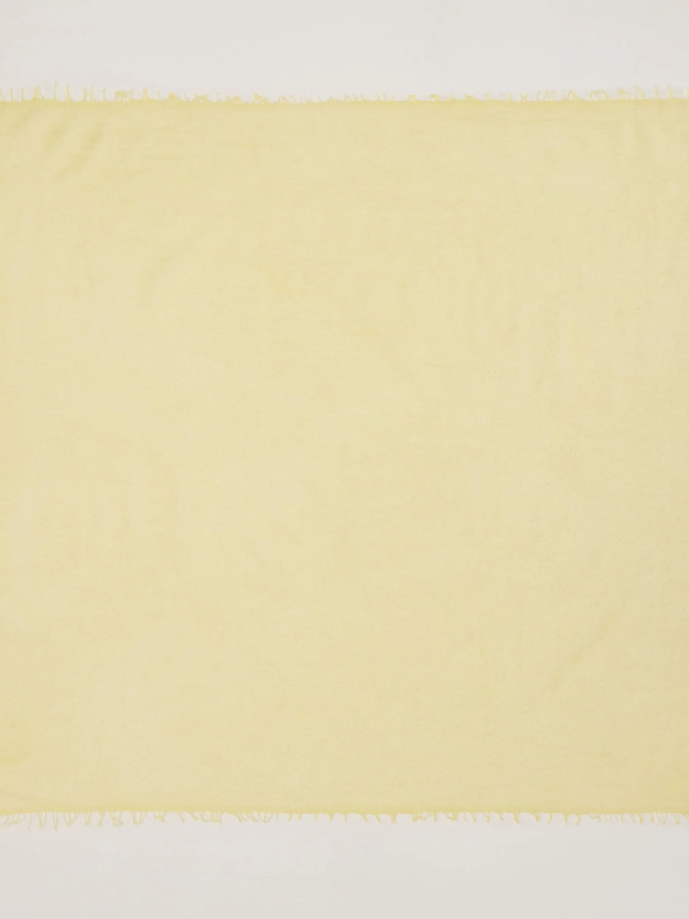 Pale yellow scarf with smooth texture and short fringed edges.