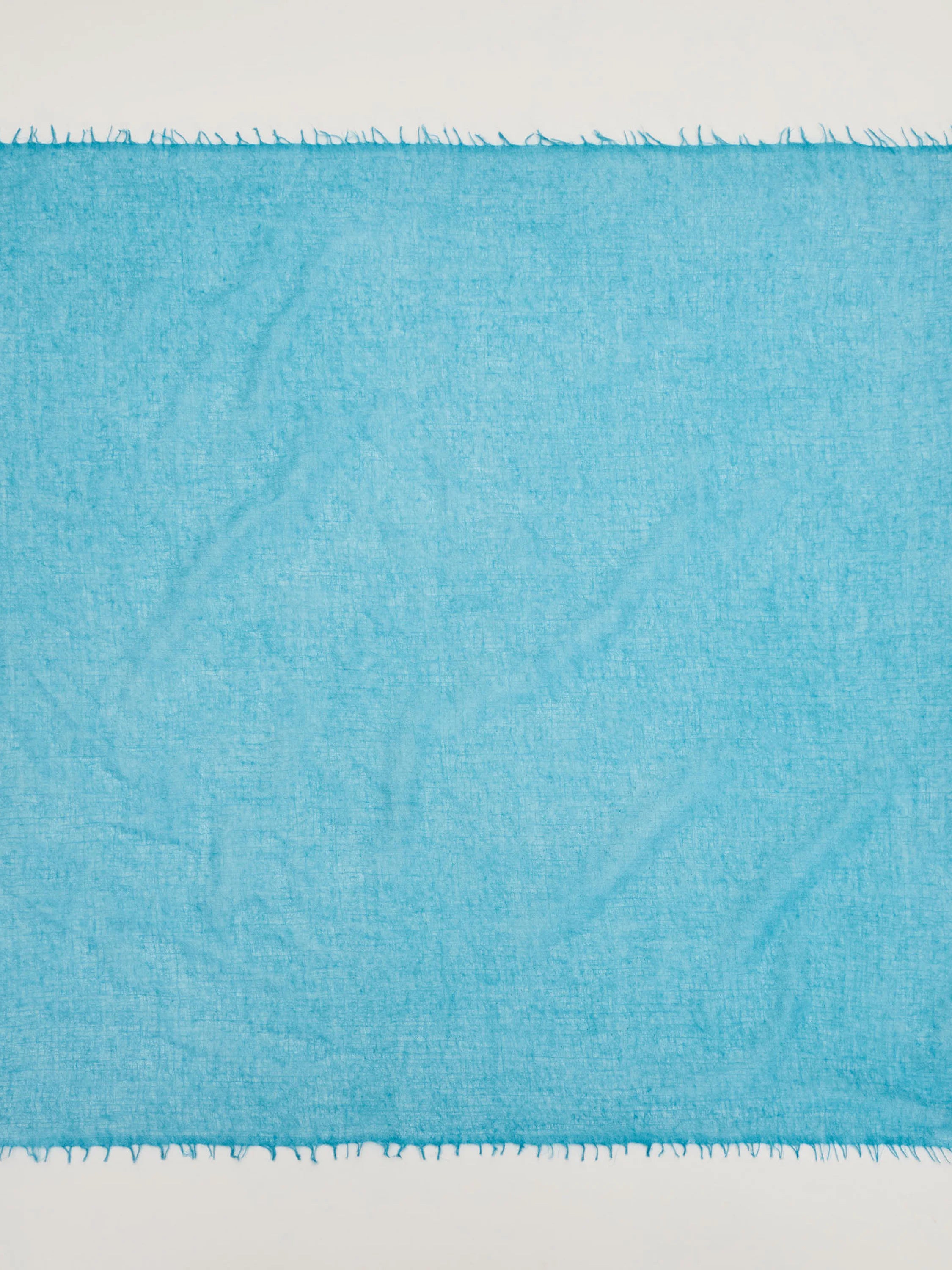 Bright turquoise cashmere neck scarf with a visible soft texture and fringed edges.