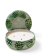 Grey-green round tin candle with a dark green pinecone pattern, white wax, and three lit wicks.