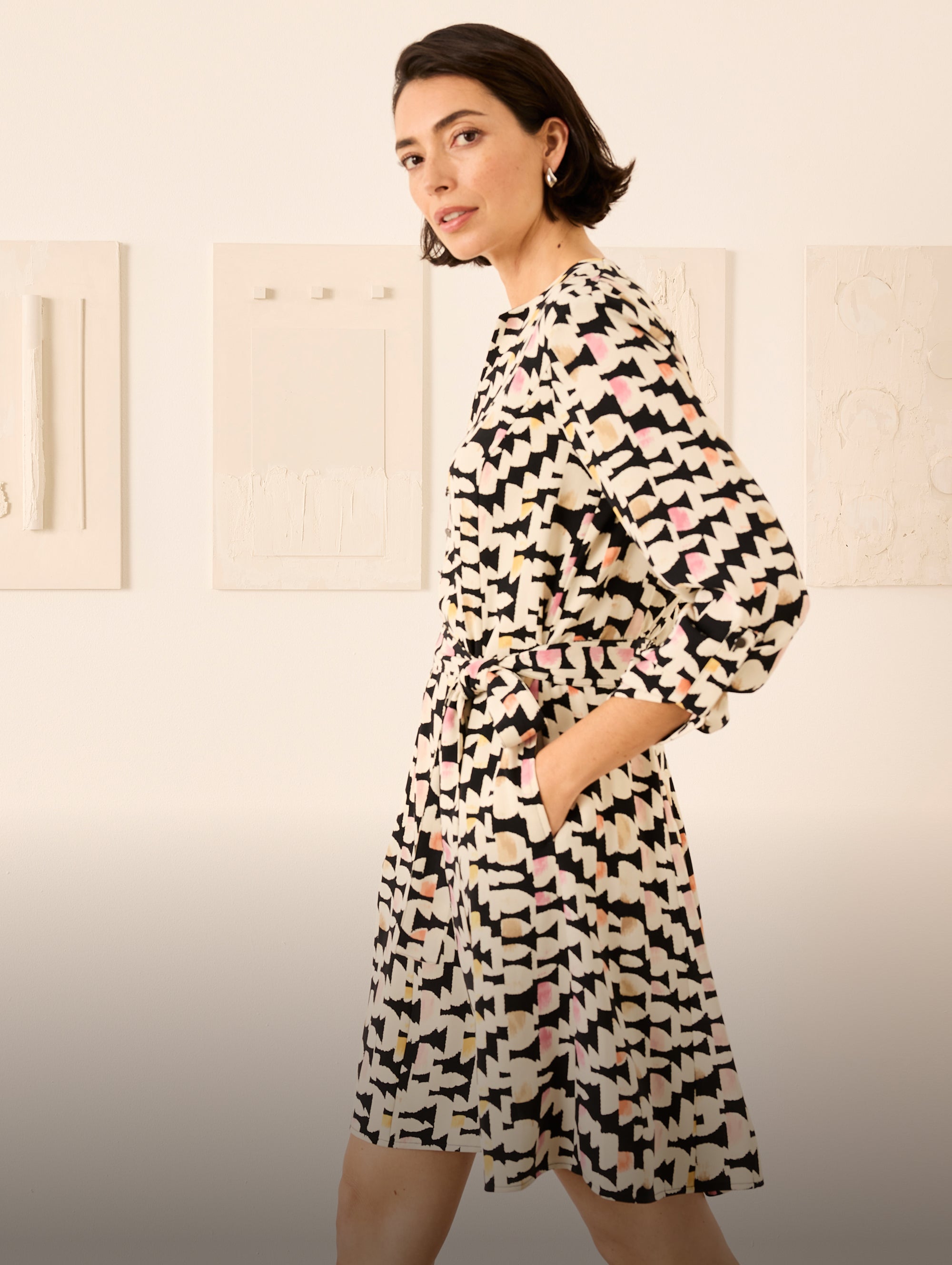 Woman wearing a patterned dress against a plain background