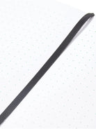 Small notebook; off-white pages with light green dots, dark gray ribbon bookmark.