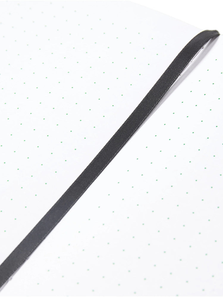 Small notebook; off-white pages with light green dots, dark gray ribbon bookmark.