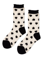 Sheer crew socks in cream feature black heart print, a black toe and heel, and a ruffled black cuff.