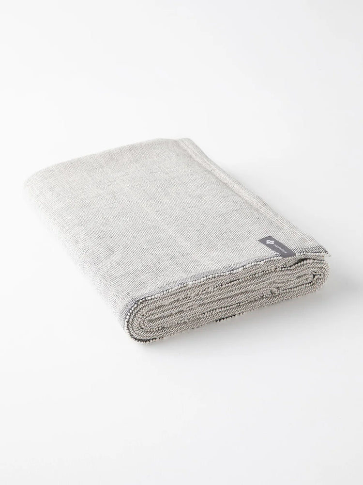 Light heather gray cotton yoga blanket, compactly rolled. Features woven texture and darker gray thread visible at edges.