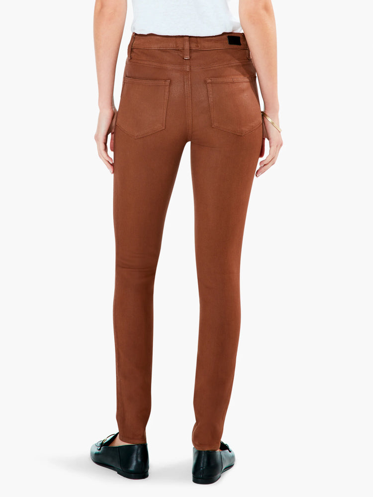 Coated copper-brown skinny ankle pants, shown from behind, with stitched back pockets.